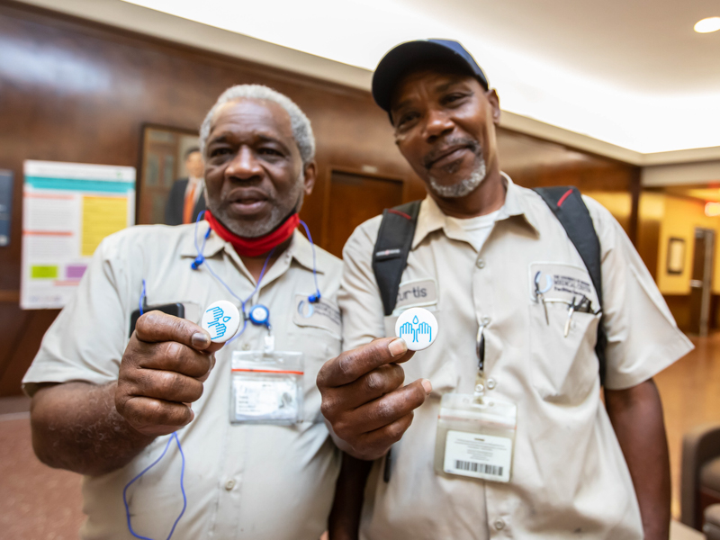 Machinery mechanic Tommy Nelson, left, and Power Plant boiler operator Curt Wilson show off their handwashing buttons. Melanie Thortis/UMMC Photography