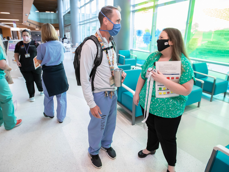Children's Hospital Director of Perioperative Services Hailey Moore greets orthopaedic surgeon Dr. Patrick Wright on World Hand Hygiene Day. Melanie Thortis/ UMMC Communications