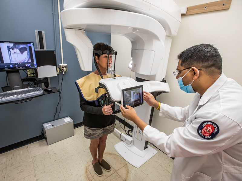 Dr. Rohan Jagtap positions a computer screen in front of patient Carol Hoover as she undergoes a cone beam CT scan at the School of Dentistry. Melanie Thortis/ UMMC Communications