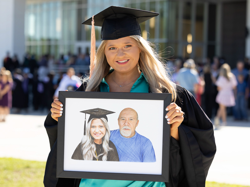 Bachelor of Science in Nursing graduate Mauri Colvin holds a portrait of herself and her late grandfather, Johnny Moorman.