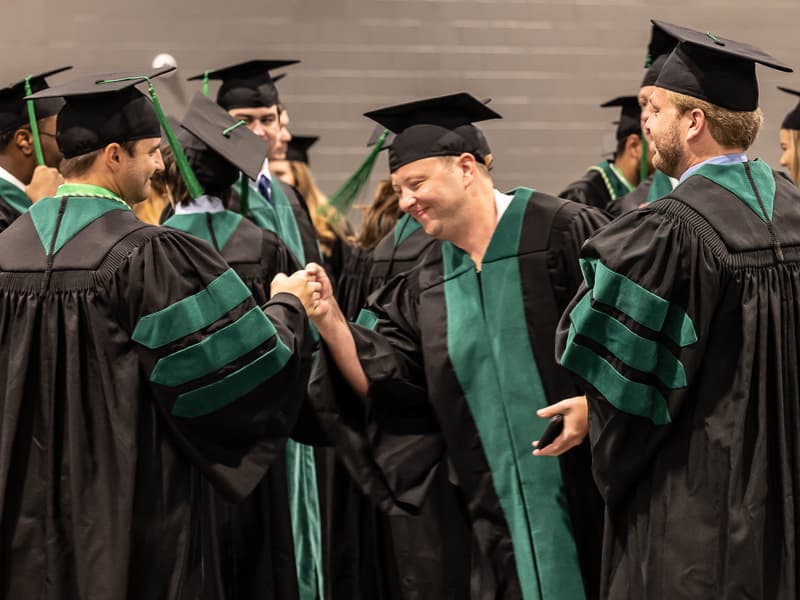 School of Medicine graduates Hunter Altman, left, and Adam Goodman fist bump prior to commencement.