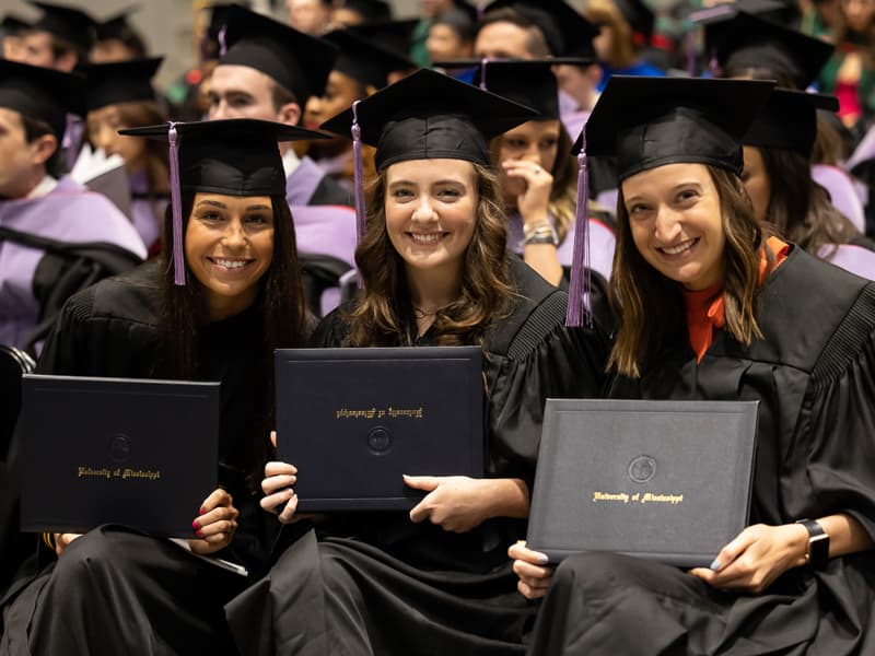 Dental hygiene graduates, from left, Allyson May, Kate McCarthy and Morgan Meek show their degree folders.