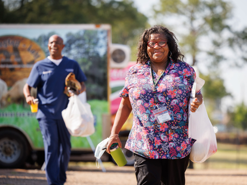 Cora Champion, a project manager with the MIND Center, leaves Thursday afternoon's Farmer's Market behind Backyard Burger with a sack of fresh vegetables. The event was sponsored by the UMMC Office of Well-being. Joe Ellis/ UMMC Communications
