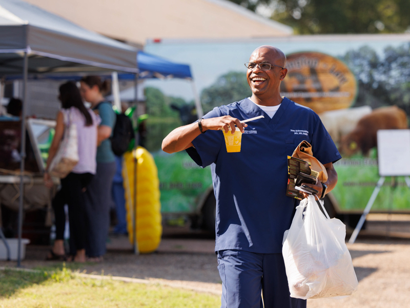 Dr. Naser Mohammedelamien, an assistant professor with Preventive Medicine, leaves Thursday afternoon's Farmer's Market behind Backyard Burger with sacks of fresh produce and a cup of juice. The event was sponsored by the UMMC Office of Well-being. Joe Ellis/ UMMC Communications 