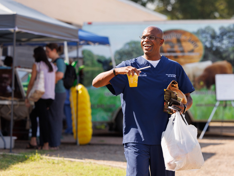 Dr. Naser Mohammedelamien, an assistant professor with Preventive Medicine, leaves Thursday afternoon's Farmer's Market behind Backyard Burger with sacks of fresh produce and a cup of juice. The event was sponsored by the UMMC Office of Well-being. Joe Ellis/ UMMC Communications