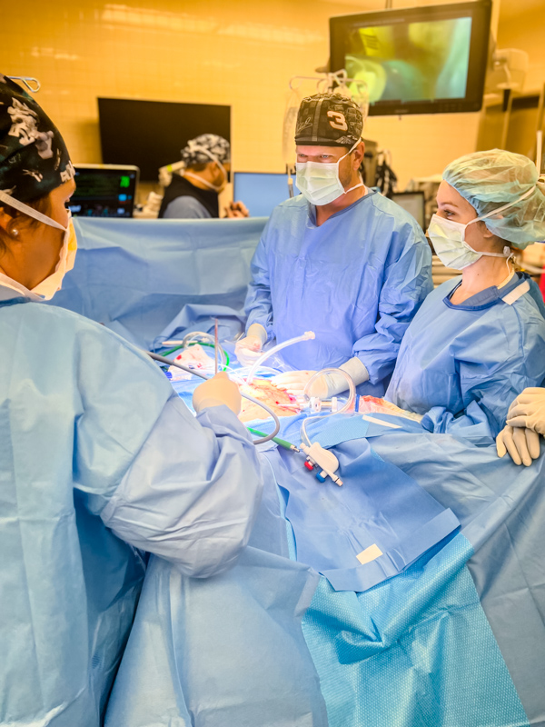 Orr, center, makes small incisions in the abdomen of Freeman as he performs the HIPEC procedure for Freeman's cancer.