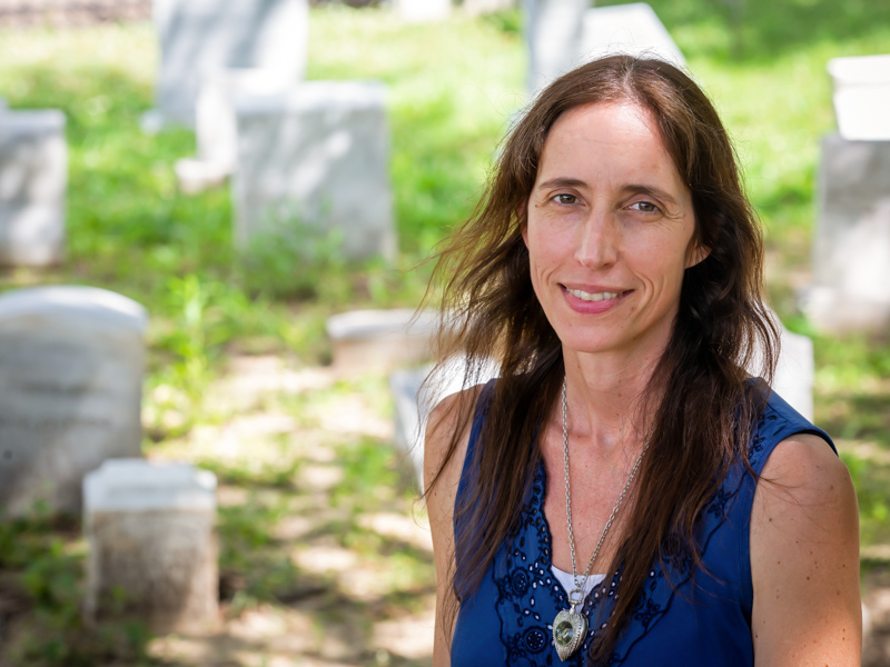 Dr. Jennifer Mack visits the UMMC Cemetery, located in the northeast corner of the campus, where human remains were reburied after being discovered on Medical Center land in 1992. Markers seen here were removed from Asylum Hill in the 1970s. For the next phase of the Asylum Hill Project, Mack will be working with human remains whose markers have disappeared. Jay Ferchaud/ UMMC Communications