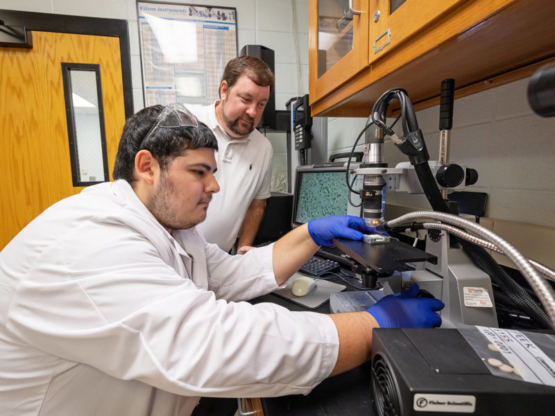 As mentor Dr. Scott Williamson watches, SURE student Oscar Dunaway performs research at the UMMC School of Dentistry. Jay Ferchaud/ UMMC Communications