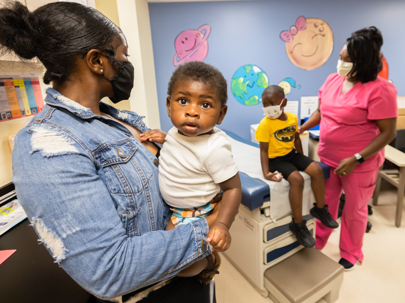 Markerria Mays holds brother Olliver Shaw, 8 months, before his COVID-19 vaccination. Olliver's older brother Omari, beside mother Kanyatice Shaw, got his vaccination first.