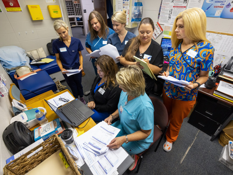 Pearl school nurses, standing, from left, Brandi Chambers, Kelley Smith, Aly Weems, Julie Thornton and Melissa Roberts watch as UMMC School of Nursing educators Jolie D'Antonio and Shanda Walenta, seated, right, go over telehealth technology.