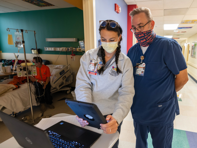 Nurse educator Baylie Leblanc and principal Epic trainer Timothy Henry prepare a MyChart Bedside tablet for patient Hayden Johnson of Laurel. Melanie Thortis/ UMMC Communications