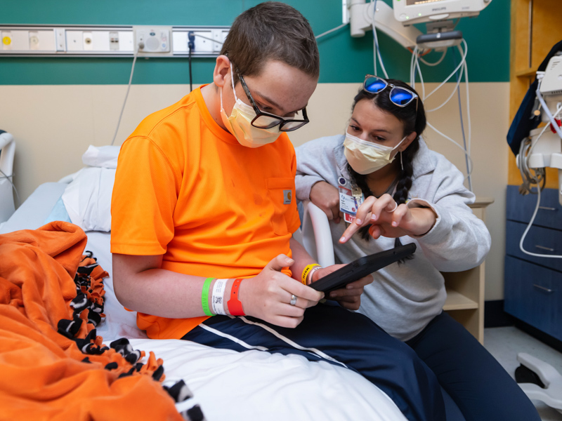 Nurse educator Baylie Leblanc shows Children's of Mississippi patient Hayden Johnson the features of MyChart Bedside and the games and entertainment options on his tablet.