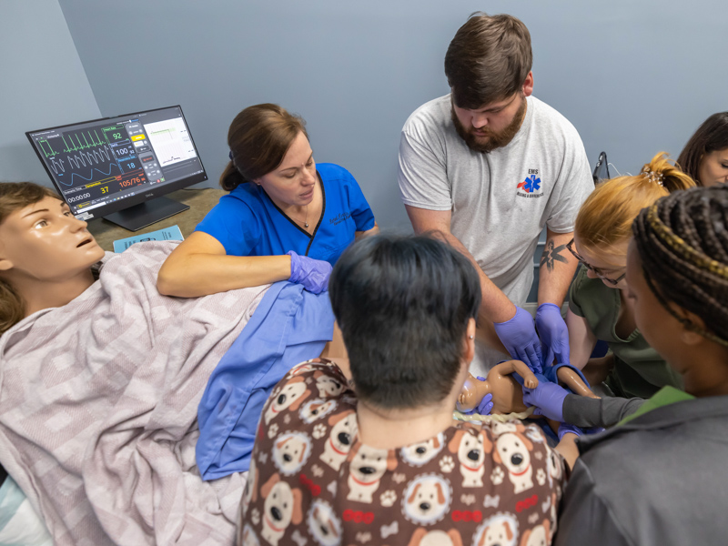Dr Rachael Morris, left, looks on as EMT Zachary Jackson and registered nurses Jordan Sawyer, Symone Ickom and Amy Haralson deliver a simulator baby during STORK training. Melanie Thortis/ UMMC Communications