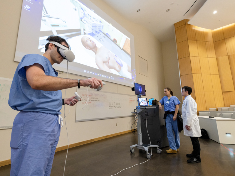 Under the guidance of Dr. Emily Tarver, center, third-year medical student Dion Kevin, wearing a virtual reality visor, takes a tour of a virtual UMMC ICU, as Dr. Norma Ojeda, right, looks on. Tarver is the co-director of virtual reality and simulation in the Division of Virtual Simulation, which is part of the Department of Advanced Biomedical Education. This is a prototype, Tarver said, and should be ready for internal testing within a couple of months. "It offers case-based training in the place of basic passive lectures," she said.