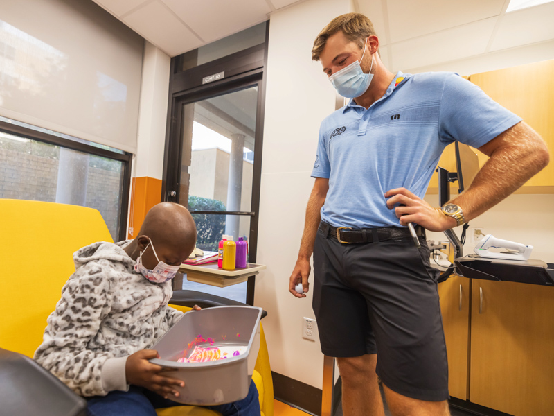 2021 Sanderson Farms Championship winner Sam Burns watches as Children's of Mississippi patient Johnette Knight of Natchez creates "golf ball" art.