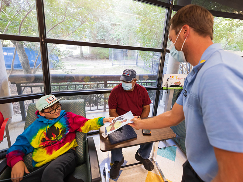 Burns gives Children's of Mississippi patient Brandon Gibson of Dalewood an autographed photo as grandfather Kerry Roberts looks on.