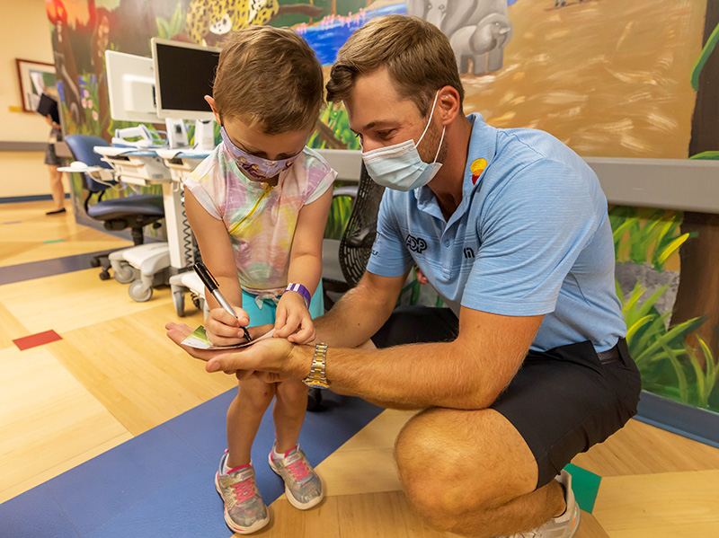 Professional golfer Sam Burns was signing autographed photos so Children's of Mississippi patient Mary Mosley of Philadelphia returned the favor. Melanie Thortis/ UMMC Communications 