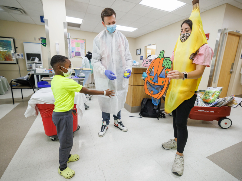 Children's of Mississippi patient Jayceston Harris of Waynesboro plays a Halloween game with volunteer Rose Garcia Ardizzoni as Dr. Jason Simpson looks on. Joe Ellis/ UMMC Communications 