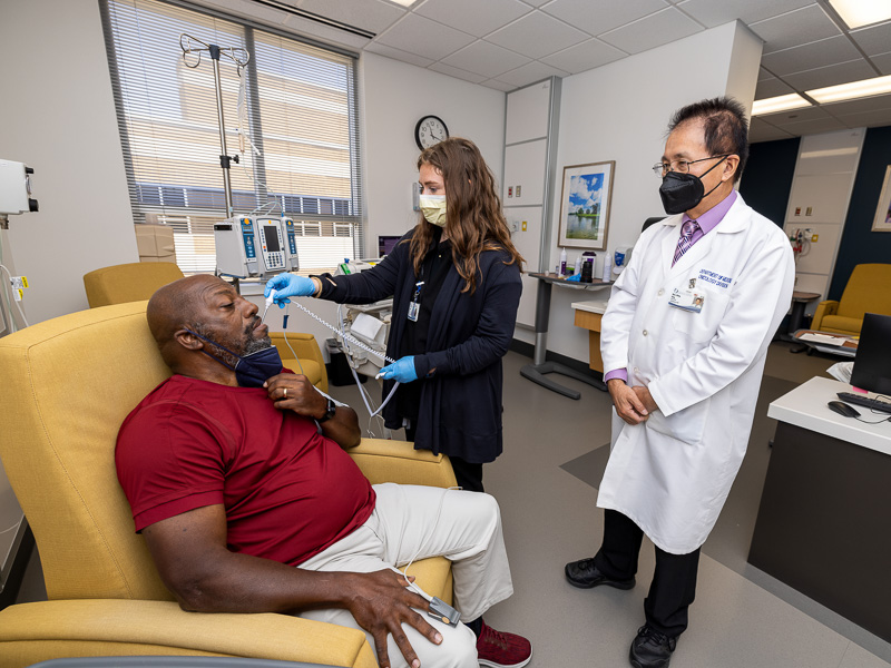 Thomas Hopkins of Bolton is examined by registered nurse Serena Flynt as part of a Phase 1 trial for a drug made by Innovent designed to boost immune function in cancer patients, while Dr. Tang watches.