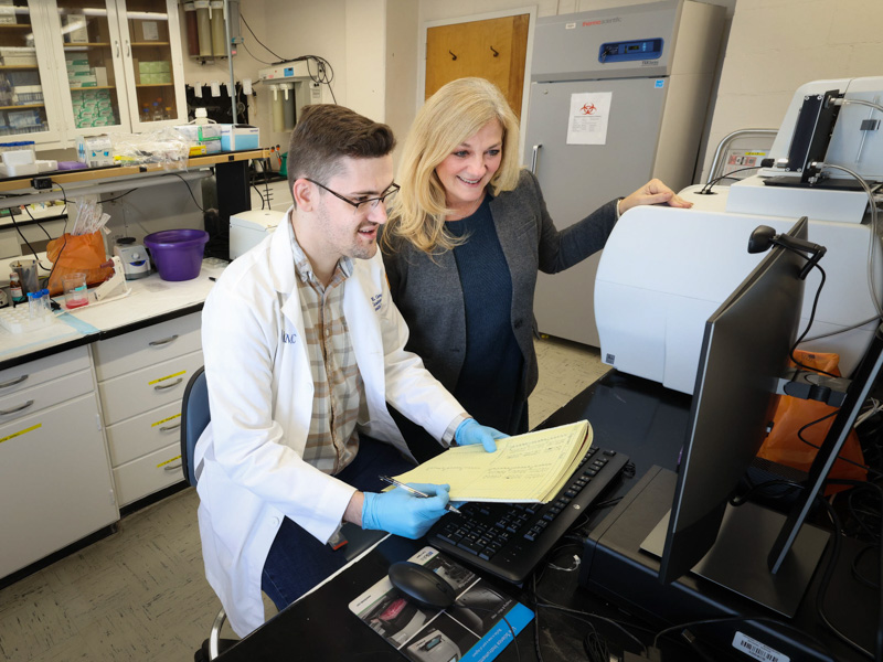 LaMarca works with doctoral student Nathan Campbell in her lab. Jay Ferchaud/ UMMC Communications
