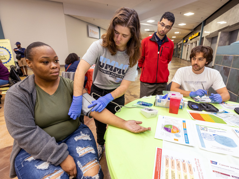 Medical student Rachael Todd, second from left, places a blood pressure monitor cuff on Angela Brown of Utica during a health screening event in Vicksburg. With Todd are two other members of the Student Health Coalition: from left, medical students Arko Dhar and Shade Smith. Jay Ferchaud/ UMMC Communications