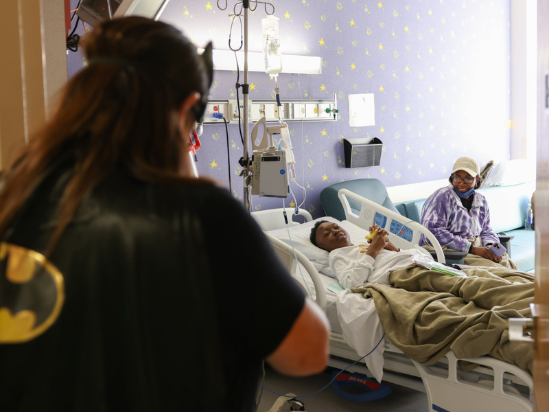 Wearing superhero gear, child life specialist Pepper Weed-Cooper visits Children's of MIssissippi patient David Thomas of Leland and his mom, LaCaron Thomas. Melanie Thortis/ UMMC Communications 