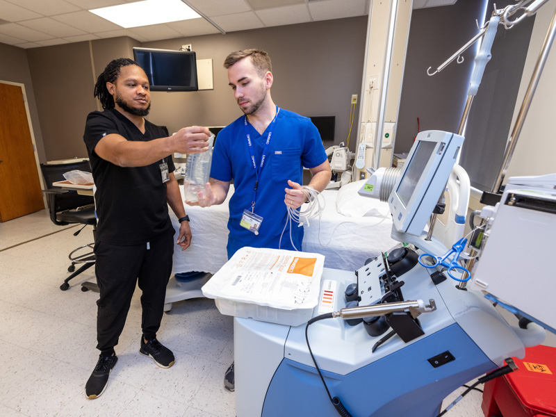 Registered nurse supervisor Shelby McNair, left, and registered nurse Caleb Pace prepare equipment they will use to remove stem cells from the blood of a BMT donor in the unit's apheresis laboratory. Jay Ferchaud/ UMMC Communications