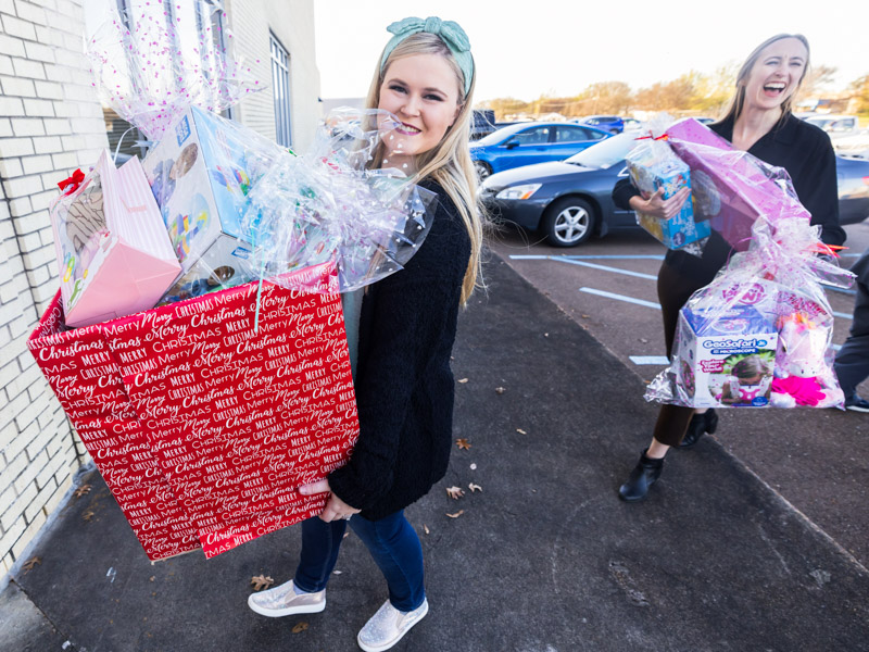Emily Davis, president of UMMC Cares and a second-year medical student, and Courtney Helfrich, director of the Children's Safe Center, carry in boxes and bags of toys. Melanie Thortis/ UMMC Communications
