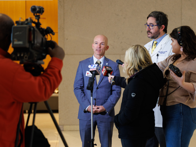 Dr. Alan Jones, center, and Dr. Peter Arnold, in white coat, speak to news media about plans for the new Mississippi Burn Center on UMMC's Jackson campus.