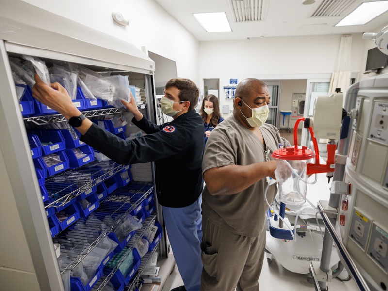 Emergency Medicine resident Dr. Andrew Garza, left, pharmacist Stephanie Tesseneer, background, and respiratory therapist Charles Patton stock supplies in a trauma room in the Adult Emergency Department at the University of Mississippi Medical Center.