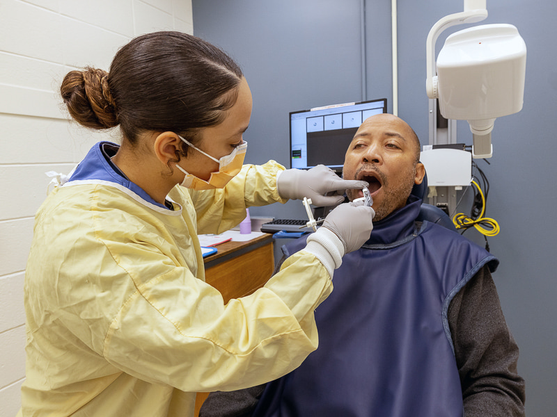 Dental hygiene student Malita Chaffier adjusts the X-ray sensor for Gene King during Dental Mission Week.