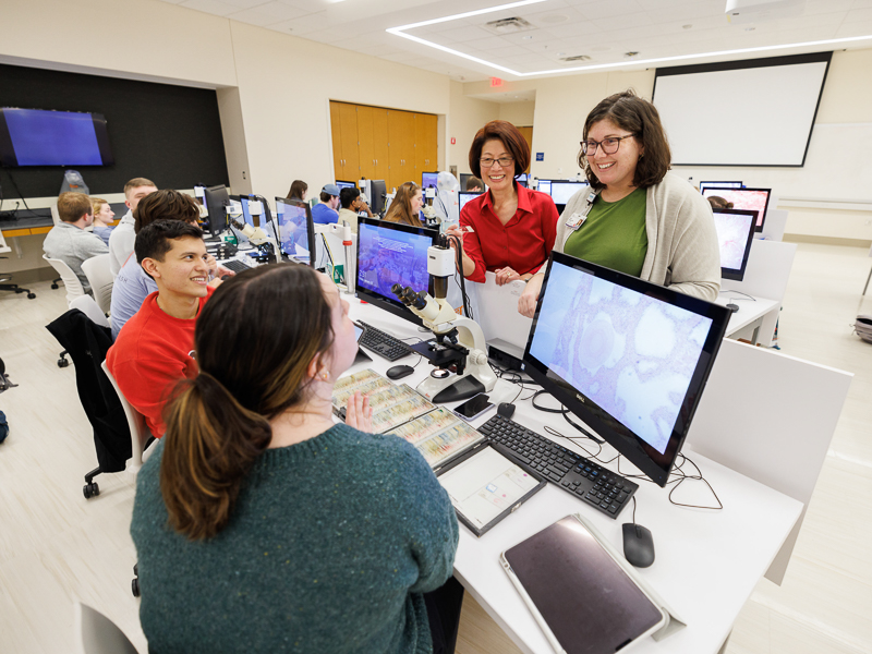 Drs. Kathleen Yee, standing left, and Audra Schaefer, talk with medical students Edgar Uribe Sanchez, left, and Ashton Swader during a recent class.