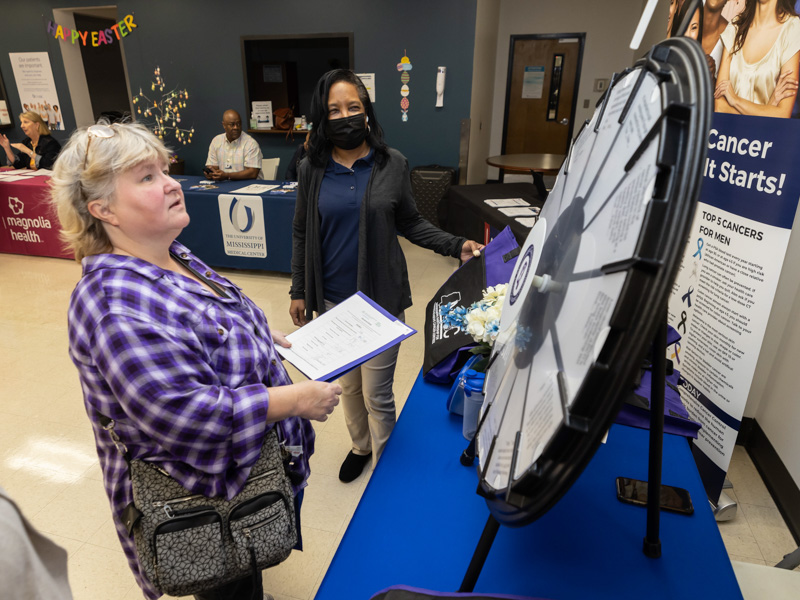 Patient Chandra D'avy spins the wheel as Deborah Morgan with the Mississippi Partnership for Comprehensive Cancer Control looks on during the See, Test & Treat event held at the Jackson Medical Mall.