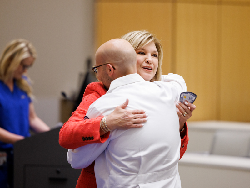 Dr. LouAnn Woodward, vice chancellor for health affairs, hugs Dr. Jonah Gunalda, an emergency medicine physician.