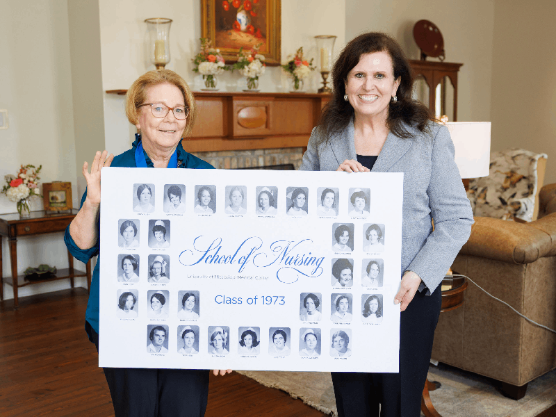 Linda Braden Thompson, a member of the School of Nursing's 1973 graduating class, and Dr. Julie Sanford, dean of the School of Nursing, hold a display of nursing school graduation photos.