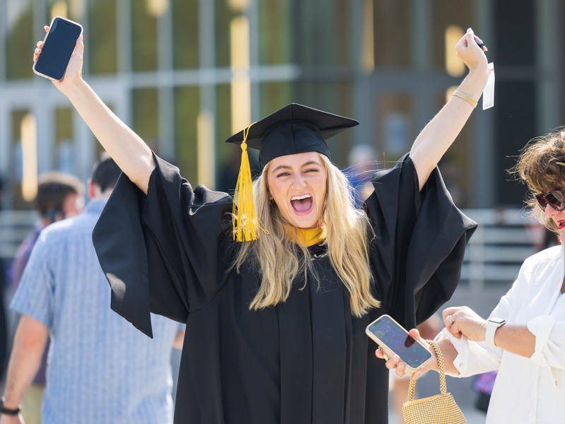 Master of biomedical sciences graduate Cara Irby spots a loved one in the crowd and cheers as her mother, Melanie Irby, prepares to enter the coliseum for commencement.