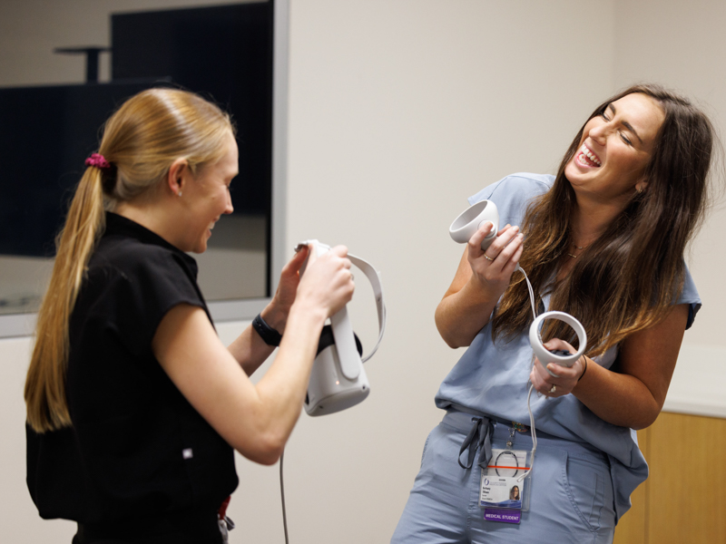 Fourth-year medical students Lauren Pole, left, and Bethany Tillman familiarize themselves with the SimGym controls during a demonstration led by Dr. Emily Tarver.
