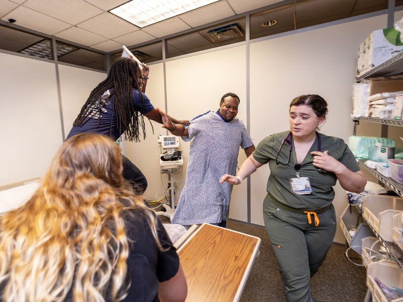 Accelerated BSN students Sarah Keaton Odom, left, and Melody Kneezel react to a simulation by officers Shanice Mays and Charles Hawthorne.
