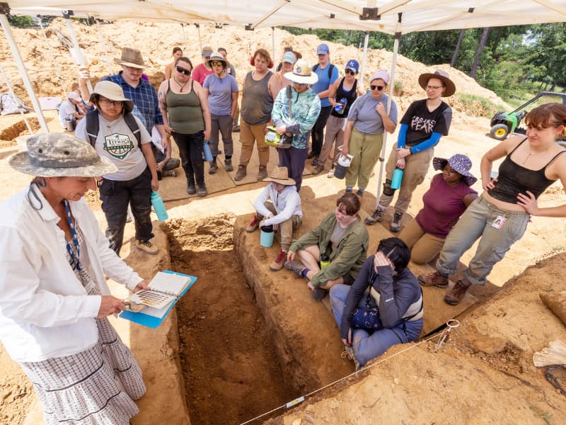 Dr. Jennifer Mack, left foreground, uses a soil book or chart to describe the variations of dirt color and what they mean, to the edification of students in the Asylum Hill Project Field School. Jay Ferchaud/ UMMC Communications