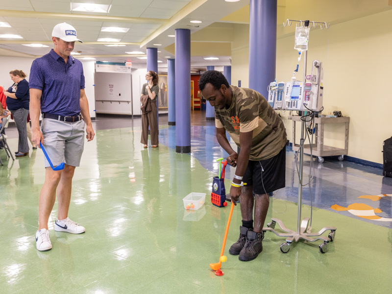 Mackenzie Hughes, the 2022 winner of the Sanderson Farms Championship, gives a putting lesson to Children's of Mississippi patient Kelvin Pierce of Glendora.