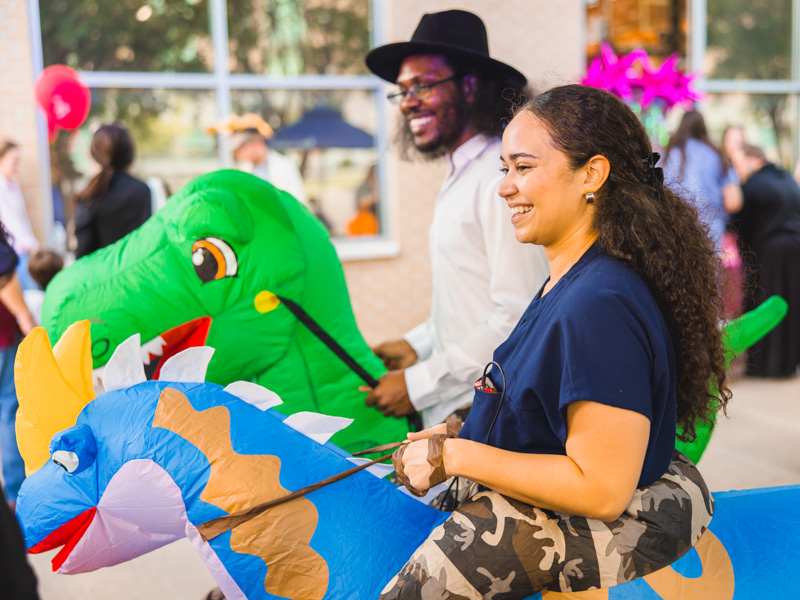 Medical students Jessica McKenzie, front, and Tyrikus Hayes rode dinosaurs to Spooky U.