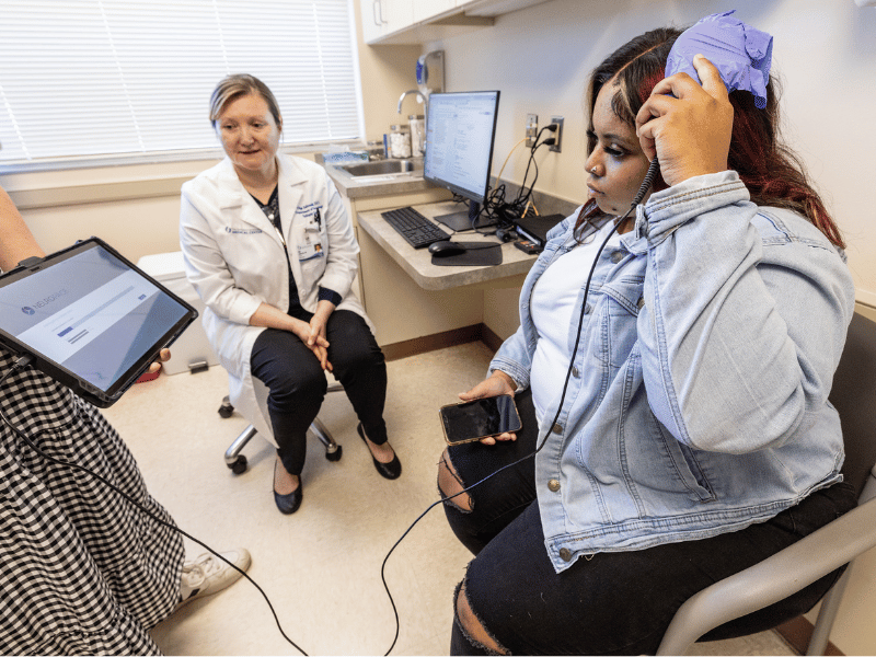 Dr. Olga Selioutski watches as Jessica Vann uploads information from her RNS device to a tablet. Jay Ferchaud/ UMMC Photography