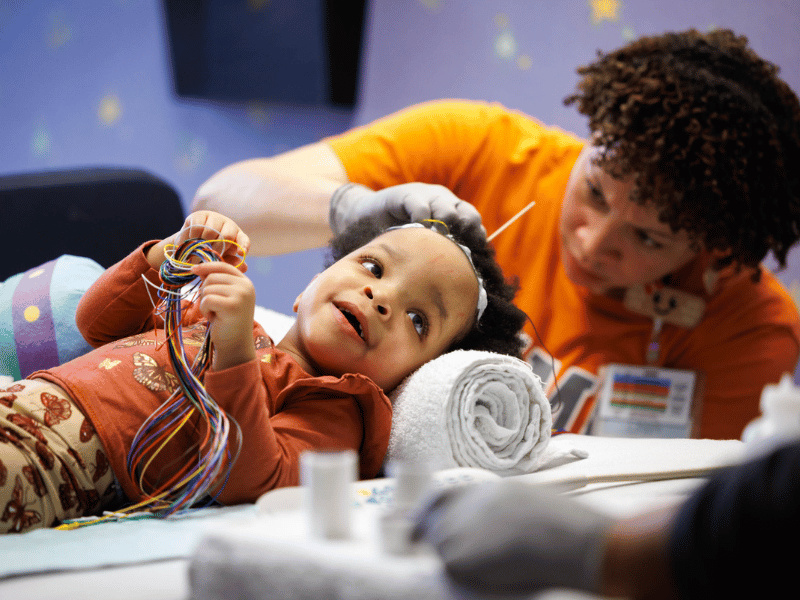 True Burns of Jackson smiles as neurophysiology tech Jazmine Anderson prepares her for an EEG at the Comprehensive Epilepsy Center at Children's of Mississippi.