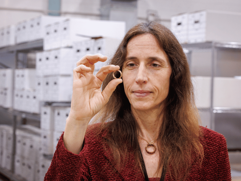 Dr. Jennifer Mack, lead bioarchaeologist for the Asylum Hill Project, displays the gold wedding ring her late husband, Dustin Clarke, discovered. It is inscribed with the words 