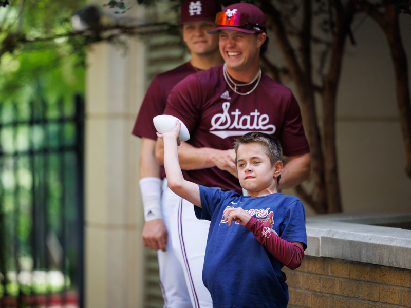 Sawyer Dykman, of Florence, a patient at Children's of Mississippi, tosses a ball during the MSU baseball team's visit to the facility.