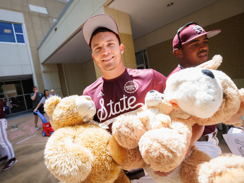 MSU catcher Johnny Long and infielder Amani Larry carry stuffed animals during the team's visit