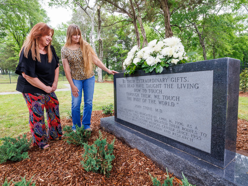 Sisters Dana Long of Hernando, left, and Jena Lynch of Vicksburg, visit the UMMC Cemetery following the Ceremony of Thanksgiving honoring anatomical donors – including their grandmother, Willie Frances Greer of Vicksburg. A donor’s remains are either returned to the family or buried in the cemetery, where this monument has been placed in their memory.