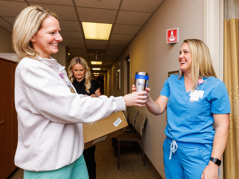 Katie Rachel, RN II, hands a UMMC-branded beverage mug to Lori Harris, diagnostic sonographer, during Employee Appreciation Week in 2024.