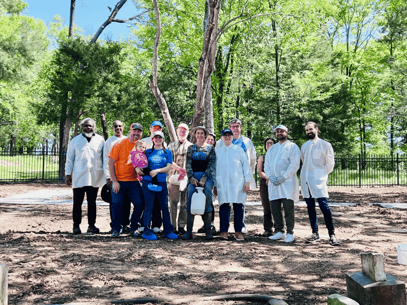 Members of the gravestone crew gather on a Saturday morning in April for a cleaning session led by Dr. Jennifer Mack, center, holding a container of the same stain remover that "keeps the White House white." Some of the UMMC volunteers' family members even pitched in. (Photo courtesy of Dr. Norma Ojeda)