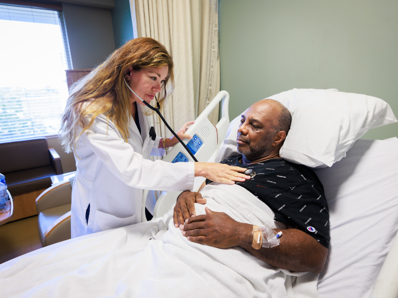 Dr. Laura Fincher, hospitalist and assistant professor of medicine, uses stethoscope to listen to patient Ronnie Green's heart and lungs.